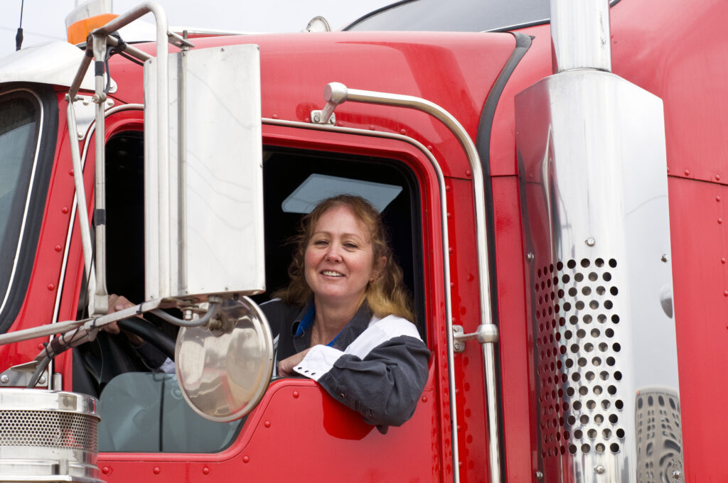 city truck driver sits in the drivers seat of a red truck.